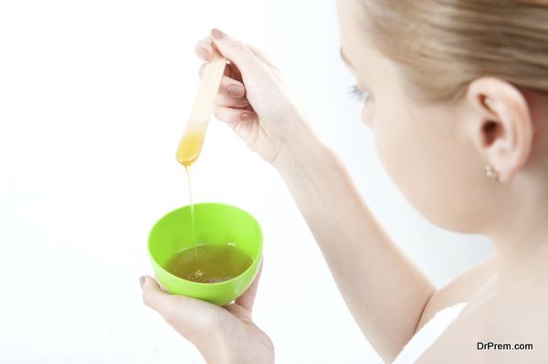 Closeup portrait of young woman in towel preparing natural homemade organic facial mask of honey, view from behind, isolated on white