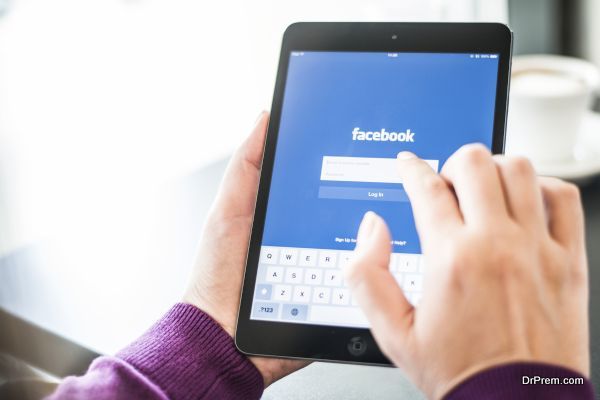 User holding an IPad with Facebook home page on screen