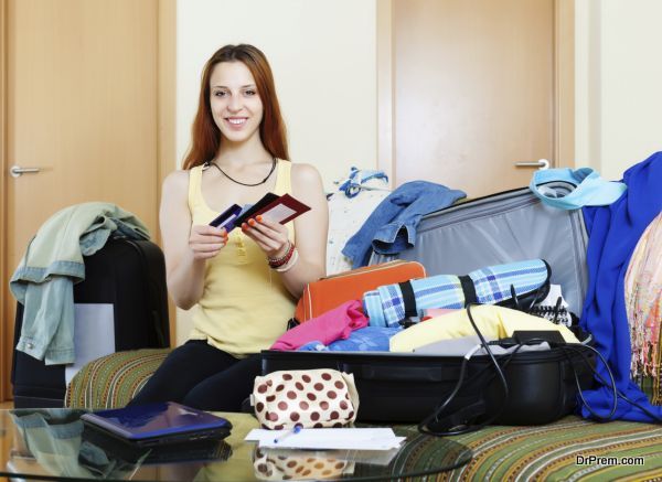 Young woman packing documents into suitcases